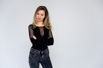 Concept of a woman talking to the camera. A photo of a pretty smiling girl with long beautiful curly hair in a black T-shirt on a white background is standing right in front of the camera.