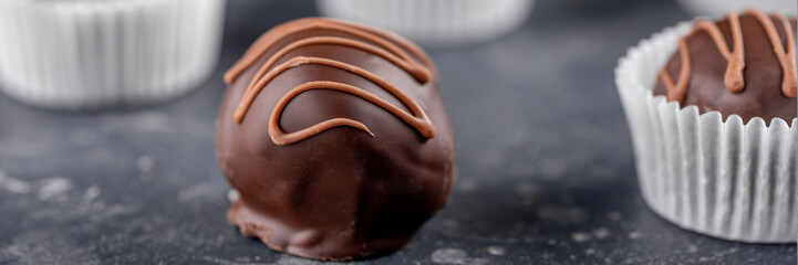 Chocolate truffle, coffee beans on a dark background. Handcrafted chocolate candy. Banner.