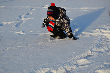 Fototapeta na wymiar cute little boy, kid in winter clothes walking under the snow, playing with snow happy