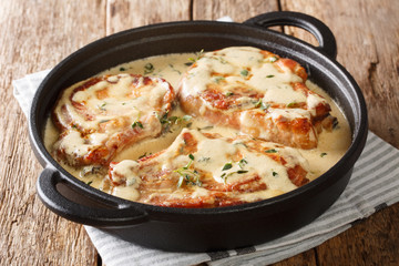 boneless pork chops served in creamy wine sauce with herbs close-up in a pan. horizontal
