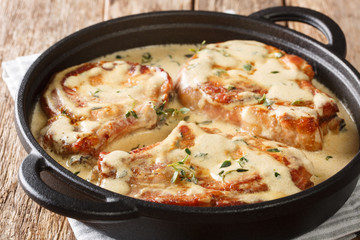 Delicious pork chops stewed in a creamy wine sauce with herbs close-up in a pan. horizontal