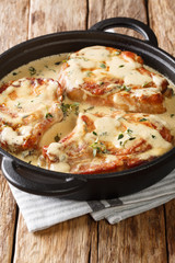 Fried pork chops stewed in a creamy wine sauce with thyme close-up in a pan on the table. vertical