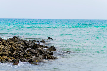 The rocks on the beach and the incoming sea water. And the sea and sky background