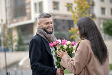 Positive dark haired woman taking a beautiful bouquet