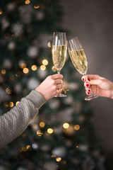 Female hands close up at christmas lights background hold champagne glasses © illustrissima