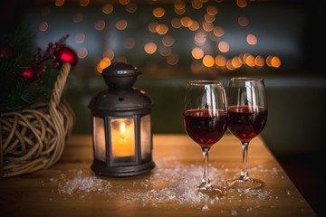 Two red wine glass on wooden loft table decorated christmas garland and lantern