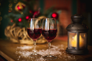 Two red wine glass on wooden loft table decorated christmas garland and lantern