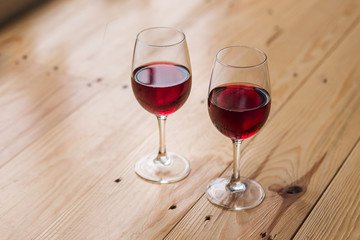 two wine glasses with red wine on wooden surface