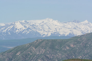 Fototapeta premium Snow peak of the mountain. Green hills. Summer. Cloudless day.