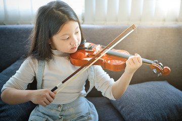 Asian kid learning and practising  to play violin at home - 306089420