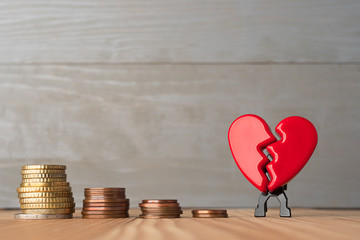 Broken red Valentine's Day heart with descending stacks of euro coins. Love and money problems...