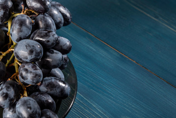 Bunch of grapes on a plate on a blue wooden background