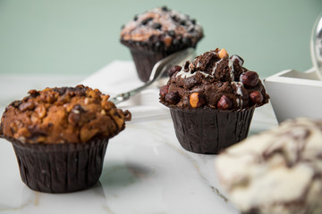 Muffin Auswahl mit Blaubeeren, Walnuss, Haselnuss und Weiße Schokolade mit Milch und Zucker für Kaffeepause auf Marmor Tisch und Grün Hintergrund