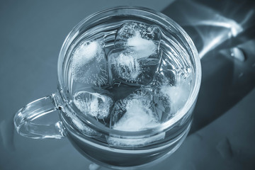 Glass of water with ice on gray background. Healthy drinking water in luxury style in monochrome color. Transparent beverage on dark backdrop.