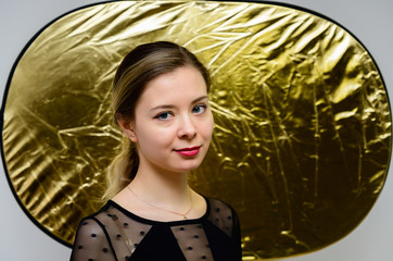 Close-up portrait of a pretty smiling girl with good make-up with clean hair on a gold background. The concept of beauty, gold, wealth.