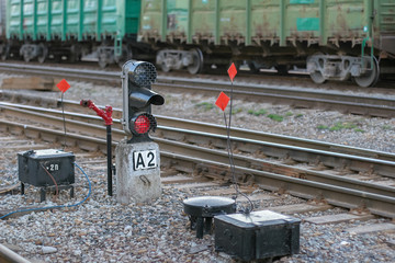 Rails with freight cars in the background and a semaphore with a glowing red light in the...