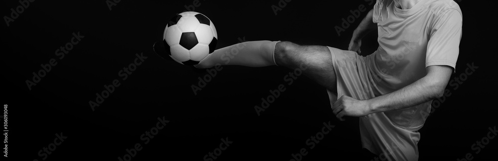 Wall mural Close up legs and soccer shoe of football player in action kicking ball isolated on black background. Black and white filter