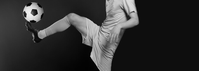Close up legs and soccer shoe of football player in action kicking ball isolated on black...