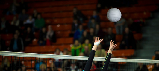 Girl Volleyball player and setter setting the ball for a spiker during a game. Team sport.