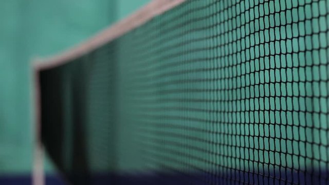 A shot of a badminton net with a shuttlecock hit the net.