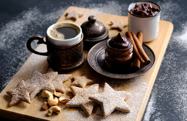 A beautiful Christmas still life of hot black coffee, homemade stars-shaped cookies, cinnamon sticks.