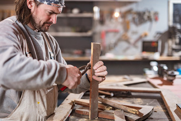 Carpenter working on a old wood in a retro vintage workshop.