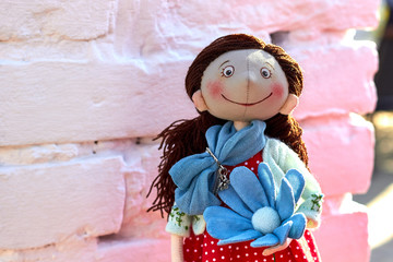 Soft textile handmade doll toy girl with a blue flower in a red dotted dress