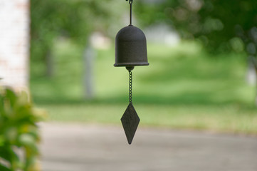 A small cast Iron wind chime with a Rhomboid striker seen hanging from a Porch of a house in Texas.