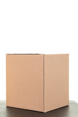 One cardboard box brown in white background black table