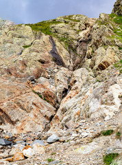 A thin brook descends from the steep slope of the mountain. The mountain stream is not wide, but strong.