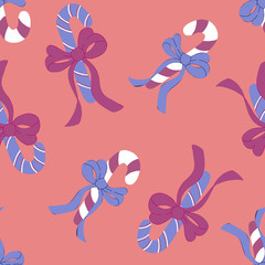 Candy canes seamless pattern with bows on peachy background. Textile and paper Christmas design.