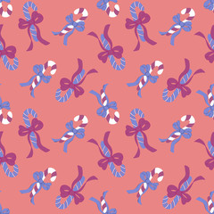 Candy canes seamless pattern with bows on peachy background. Textile and paper Christmas design.