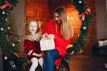Beautiful mother in a red sweater. Family with cristmas gifts. Little girl near christmas tree