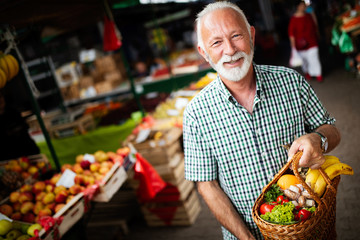 Handsome senior man shopping for fresh fruit and vegetable in a market