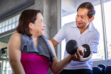 Fototapeta na wymiar Asian senior couple smiling in sportswear exercising at gym.