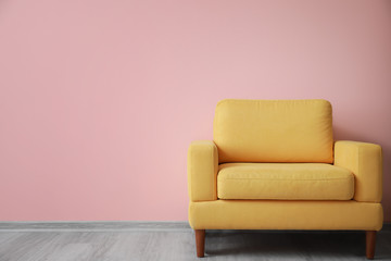 Stylish armchair near color wall