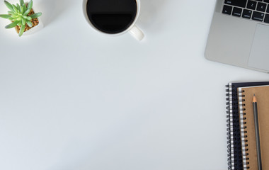 Flat lay, White office desk table with laptop, notebooks, pencil and black coffee cup. Top view with copy space.