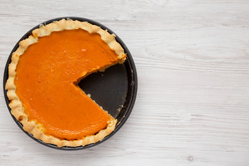 Homemade Thanksgiving pumpkin pie on a white wooden surface, top view. Overhead, from above, flat lay. Copy space.