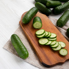 Fresh mini baby cucumbers on a rustic wooden board, side view. Close-up.