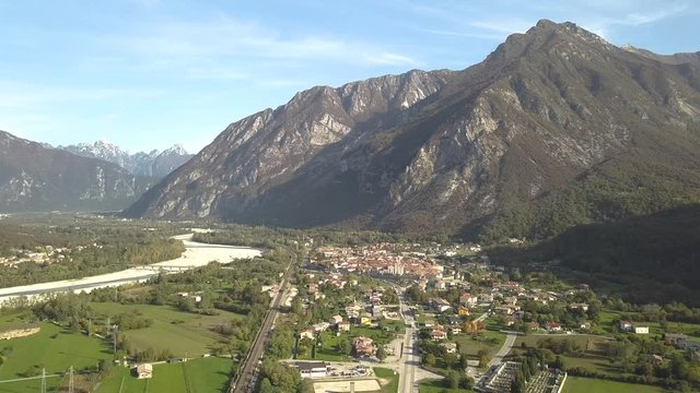 Aerial view of a small historic town Venzone in Northern Italy with red tiled roofs of old buildings and majestic Alps mountains.