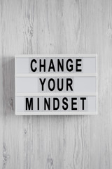Overhead view, 'Change your mindset' words on a lightbox on a white wooden background. Top view, from above, flat lay.