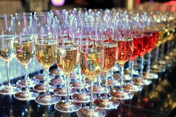 Rows of full champagne, sparkling wine and red wine glasses. Dining, drink. Catering service concept.