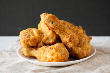 Delicious homemade oven baked fried chicken on a white plate, side view. Closeup.