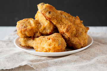 Homemade crispy oven baked fried chicken on a white plate, side view. Closeup.