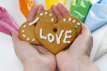 Christmas gingerbread cookies in hand with colored sweet icing. gingerbread cookies with white text Love