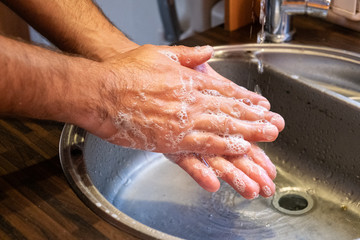 A man washes his hands in the sink under the pressure of clean water. Healthy lifestyle. Body hygiene.