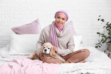 Portrait of beautiful Muslim woman with cute dog in bedroom