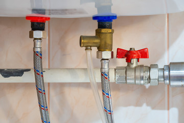 Detail of tap and tube of an electric water boiler in bathroom