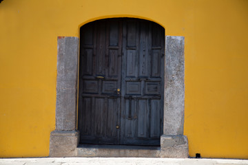 Old door in colonial city with yellow wall- Antigua Guatemala