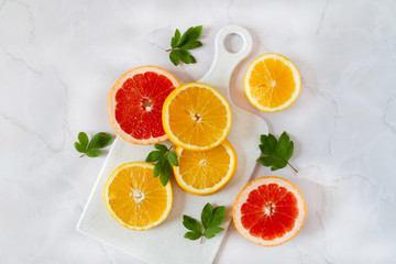 Oranges flatlay. Beautiful healthy summer background. Fresh fruits sliced on a white marble table.